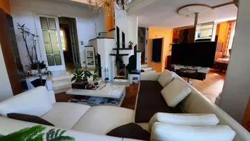 Geräumiges Wohnzimmer mit hohen Decken, großer Couch und modernem Unterhaltungssystem.