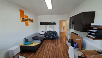 Helles Wohnzimmer mit Holzparkettboden, Sofa und einem Arbeitsbereich.