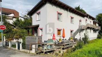 Mehrfamilienhaus mit mehreren Balkonen und Terrassen in ländlicher Umgebung.