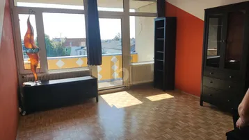 Helles Zimmer mit Parkettboden, orangefarbenen Wänden und direktem Zugang zu einem Balkon.