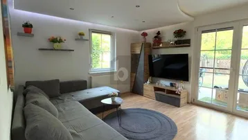 Helles Wohnzimmer mit großem Ecksofa, Holzboden und Zugang zum Gartenbereich.