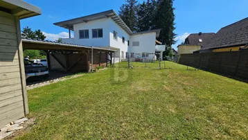 Modernes Einfamilienhaus mit großem Garten und Carport im Grünen.