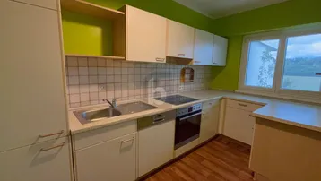 Funktionale Küche mit weißen Schränken, Fliesenrückwand und grünen Wänden.
