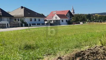 Weitläufige Grünfläche mit Blick auf umliegende Wohnhäuser und eine Kirche im Hintergrund.