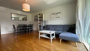 Helles Wohn- und Esszimmer mit Holzparkettboden, bequemer Couch und Esstisch für vier Personen.
