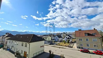 Weitblick über die Stadt und die umliegende Berglandschaft unter blauem Himmel.