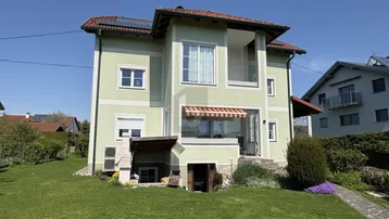 Außenansicht des Hauses mit gepflegtem Garten, Rasenfläche und Photovoltaikanlage auf dem Dach.