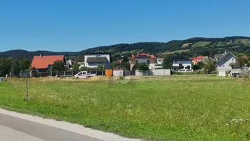 Weitläufiges Grundstück mit Blick auf die umliegende Wohnbebauung und grüne Hügellandschaft.