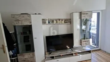 Helles Wohnzimmer mit modernem TV-Möbel und Zugang zum Balkon.