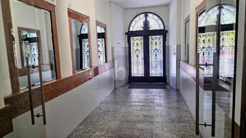 Eingangsbereich mit Granitboden, hohen Decken und dekorativer Eingangstür im Altbau.