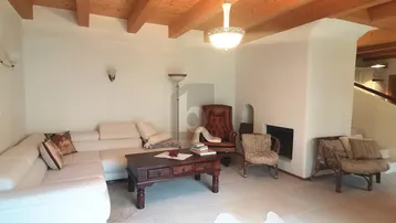 Gemütliches Wohnzimmer mit großem Sofa, Kamin und charakteristischer Holzbalkendecke.