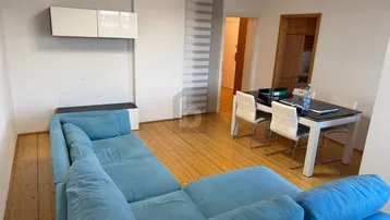 Heller Wohn- und Essbereich mit blauem Ecksofa, Holzboden und Esstisch.