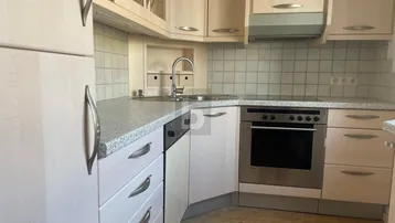 Funktionale Küche mit hellen Holzschränken, integriertem Backofen und praktischer Arbeitsplatte.
