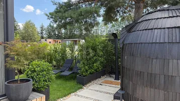Gepflegter Gartenbereich mit Liegestühlen und einer einzigartigen, runden Holzstruktur.