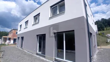 Moderne Fassade eines Neubaus mit großen Fenstern und zweifarbiger Gestaltung.