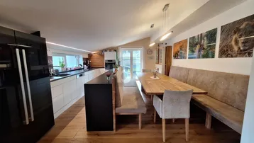 Moderne offene Küche mit Essbereich, Holzboden und schrägen Decken, ideal für geselliges Beisammensein.