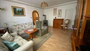 Gemütliches Wohnzimmer mit Holzboden, Kaminofen und traditionellen Möbeln.