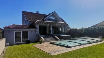 Großzügiger Gartenbereich mit Rasenfläche, Pool und Blick auf die moderne Hausfassade.