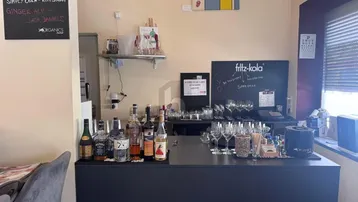 Eine gut ausgestattete Bar mit Flaschen, Gläsern und einer Tafel mit Getränkeangeboten in einem Innenraum.