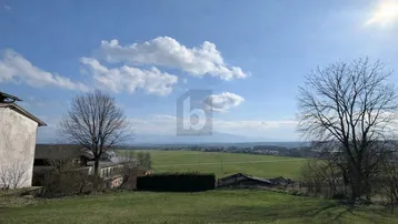 Weitläufige grüne Landschaft mit Fernblick auf die Berge unter einem strahlend blauen Himmel.