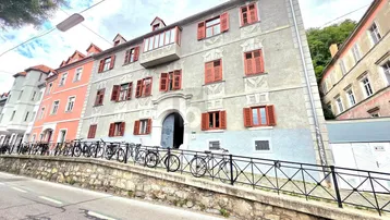 Historisches Gebäude mit roten Fensterläden und Fahrrädern an der Straße.