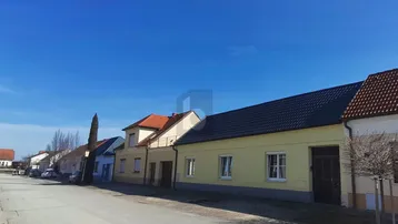 Blick auf eine ruhige Straße mit mehreren Wohnhäusern unter einem klaren blauen Himmel.