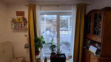 Helles Zimmer mit Zugang zu einem Balkon oder einer Terrasse und Blick auf die umliegende Natur.