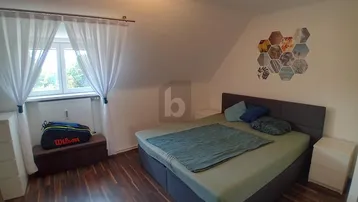 Helles Schlafzimmer mit Doppelbett, Dachschräge und Fenster mit Blick ins Grüne.
