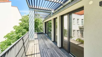 Geräumige Holzterrasse mit moderner Pergola und Blick ins Grüne, ideal für Entspannung im Freien.