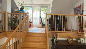 Helle Holztreppe führt zu einem oberen Wohnbereich mit Blick ins Grüne.