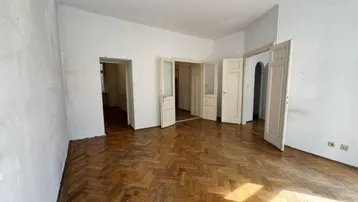 Geräumiges Wohnzimmer mit Fischgrätparkett und mehreren Türen zu angrenzenden Räumen.