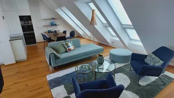 Helles, offenes Wohnzimmer mit Dachschrägen, Holzboden und modernen Möbeln.