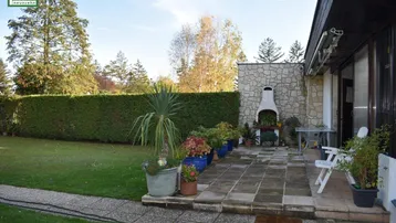 Geräumige Terrasse mit gepflastertem Boden und einem gemauerten Grillplatz für gemütliche Abende.