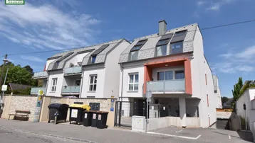 Moderne Wohnanlage mit mehreren Balkonen und Mansarddach, direkt an der Straße gelegen.