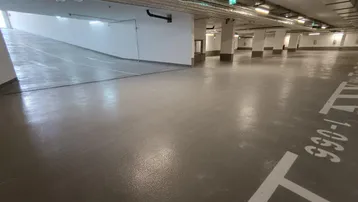 Geräumige Tiefgarage mit Zufahrtsrampe, vielen Stellplätzen und moderner Beleuchtung.