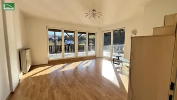 Helles Wohnzimmer mit Parkettboden und Zugang zu einem großen Balkon mit Bergblick.