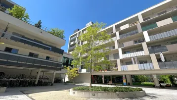 Moderne Wohngebäude mit Balkonen und einem begrünten Innenhof, ideal für Fahrradabstellplätze.