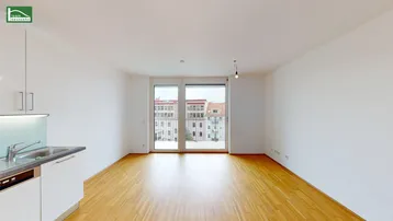 Heller Wohnbereich mit großen Fenstern, Holzboden und Zugang zu einem französischen Balkon.