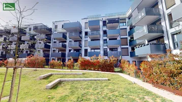 Moderne Wohnanlage mit mehreren Gebäuden, Balkonen und begrünten Außenbereichen.