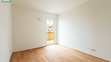 Heller, leerer Raum mit Holzboden und Zugang zu einem Balkon, ideal für individuelle Gestaltung.
