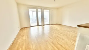 Helles, leeres Zimmer mit Holzboden und großen Fenstertüren, die zu einem Balkon mit Bergblick führen.