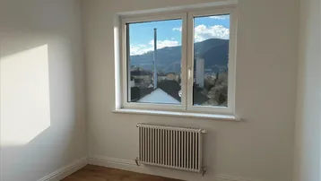 Heller Raum mit Holzboden und Fenster, das einen weiten Blick auf die Berge bietet.