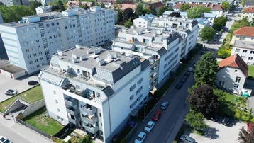 Luftaufnahme einer modernen Wohnanlage mit mehreren Gebäuden und umliegender Stadtlandschaft.