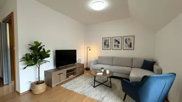 Helles Wohnzimmer mit modernem Sofa, TV-Möbel und Holzboden.