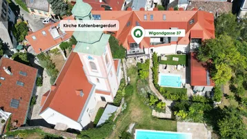 Luftaufnahme der Kirche, umgeben von Weinbergen und Wohngebäuden mit privaten Pools.