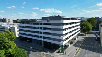 Modernes Mehrfamilienhaus mit klarer Architektur und mehreren Etagen in städtischer Umgebung.