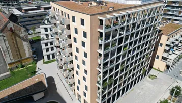 Moderner Wohnkomplex mit vielen Balkonen und begrüntem Flachdach in städtischer Umgebung.