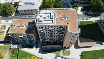 Vogelperspektive auf einen modernen Wohnkomplex mit Flachdächern und weitläufigen Grünflächen.