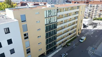Luftaufnahme des modernen Wohnkomplexes mit Flachdach und umliegender Stadtlandschaft.