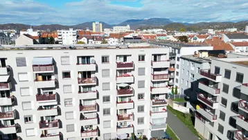 Wohngebäude mit zahlreichen Balkonen und weitem Blick über die Stadt bis zu den Bergen.